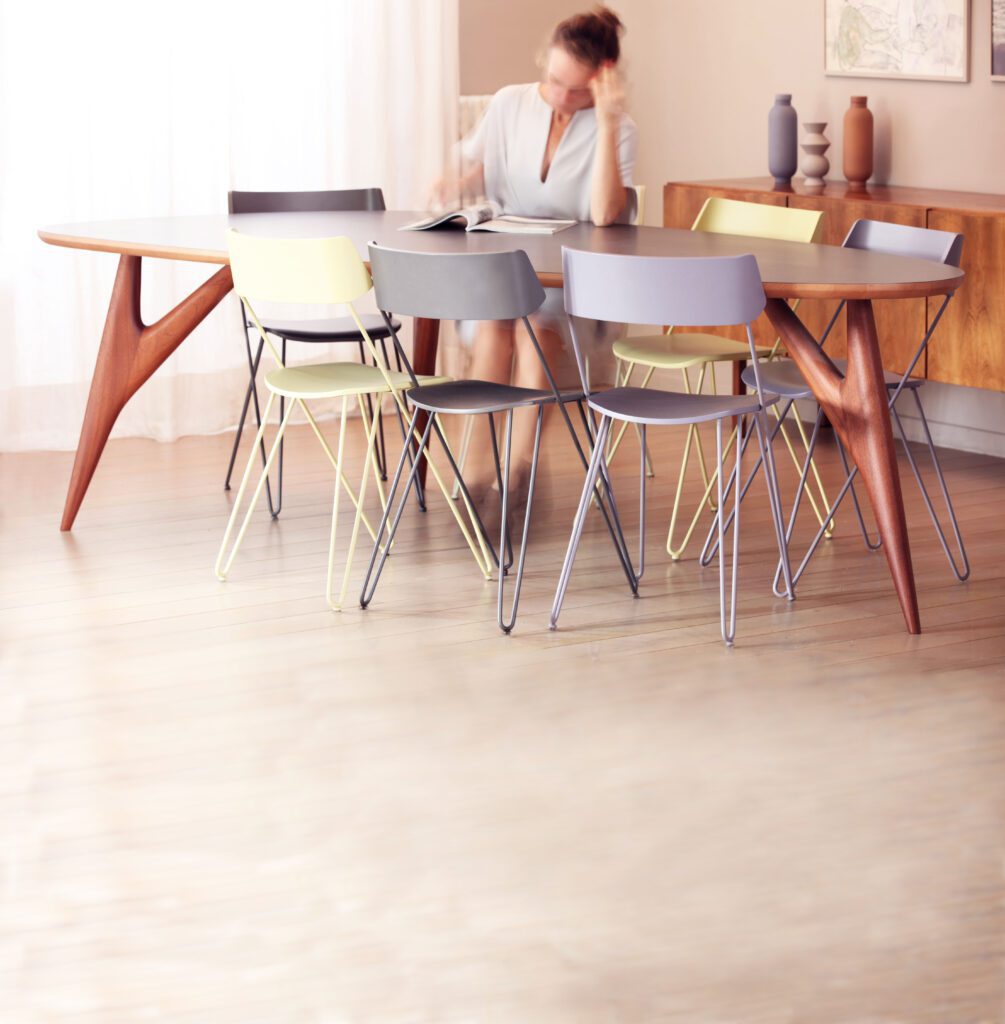 Full view of the Ted One Grey dining table, elegantly staged with Ibsen chairs and a young woman in a sophisticated atmosphere.